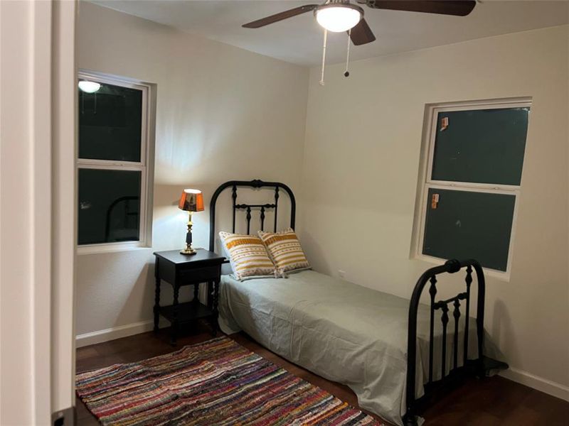 Room featuring wood-finish flooring, white baseboards, and two single-hung windows