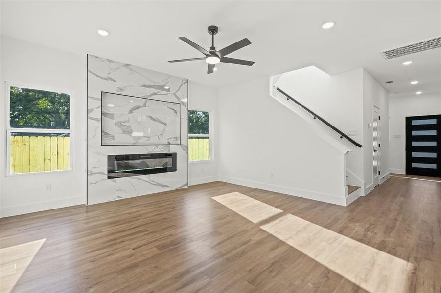 Unfurnished living room with recessed lighting, a premium fireplace, wood finished floors, a ceiling fan, and stairway