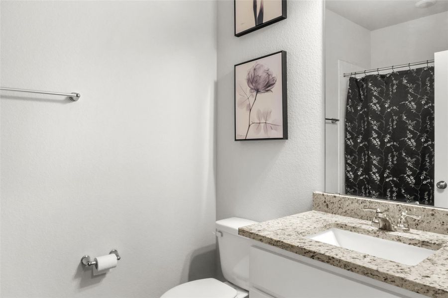 Bathroom with a shower with curtain, vanity, and a textured wall