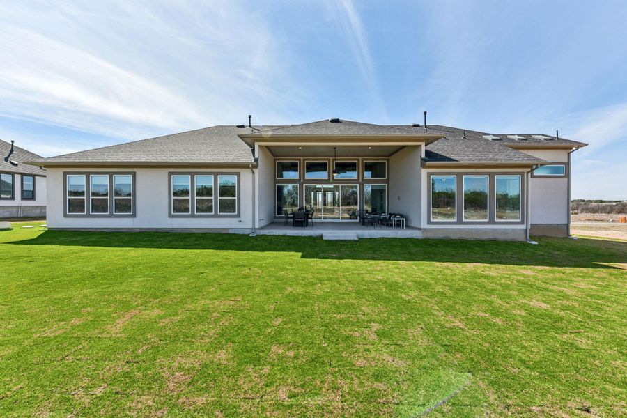 Rear view of property featuring a patio area, stucco siding, and a lawn