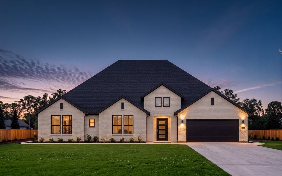 Single-story white brick home with dark roof, two-car garage, and lit exterior at dusk Single-story white brick home with dark roof, two-car garage, and lit exterior at dusk
