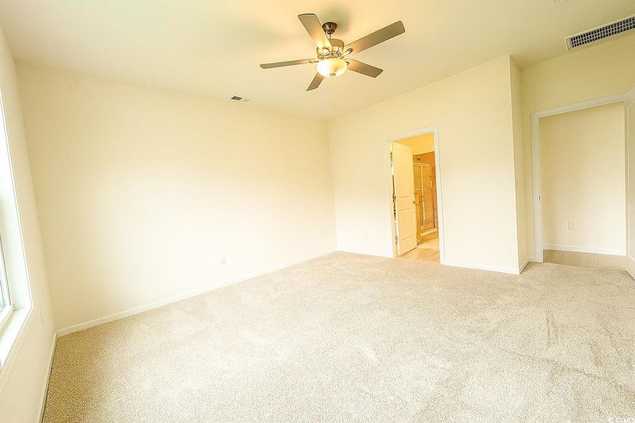 Unfurnished bedroom with light colored carpet, ceiling fan, and ensuite bath Unfurnished bedroom with light colored carpet, ceiling fan, and ensuite bath
