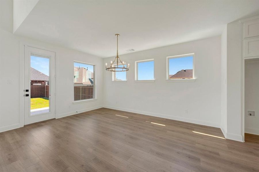 Spacious interior featuring wood-finish flooring, white walls, and a contemporary chandelier