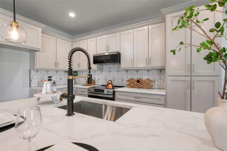 Kitchen with backsplash, light stone countertops, hanging light fixtures, and recessed lighting