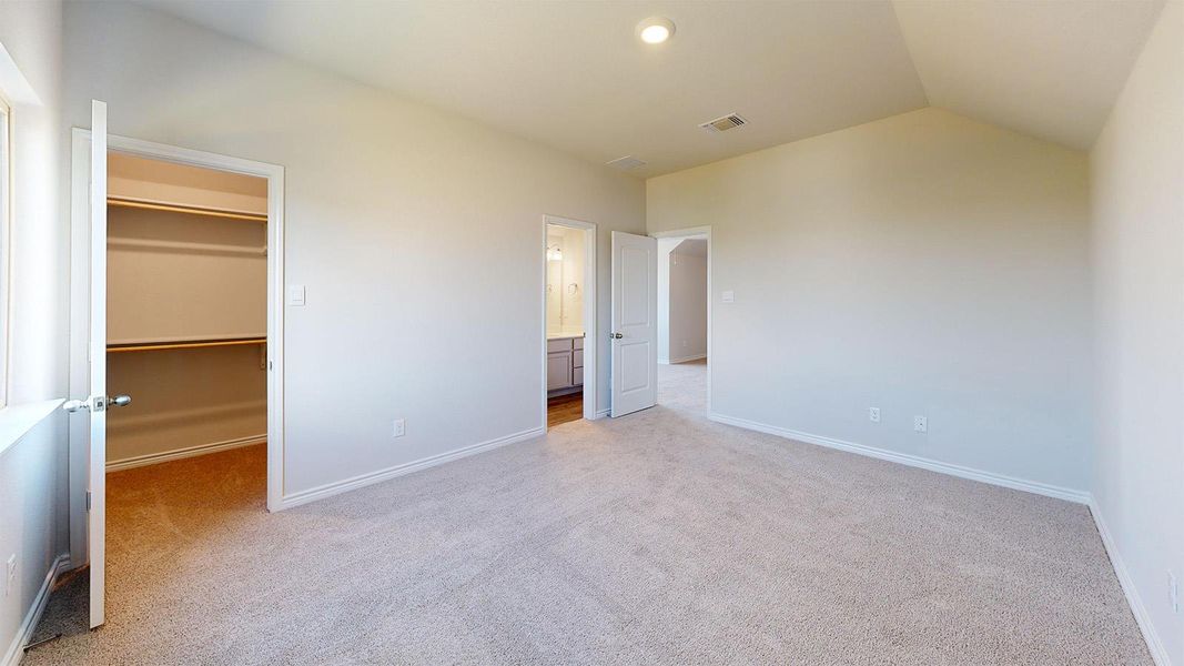 Unfurnished bedroom featuring a spacious closet, light carpet, vaulted ceiling, and ensuite bath Unfurnished bedroom featuring a spacious closet, light carpet, vaulted ceiling, and ensuite bath