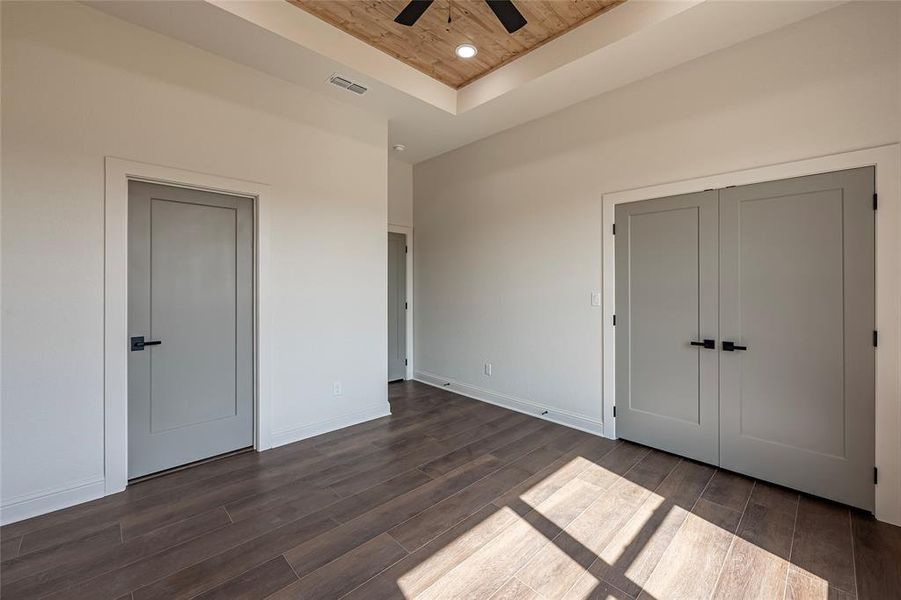 Unfurnished bedroom featuring wood ceiling, a raised ceiling, dark wood-type flooring, a ceiling fan, and recessed lighting