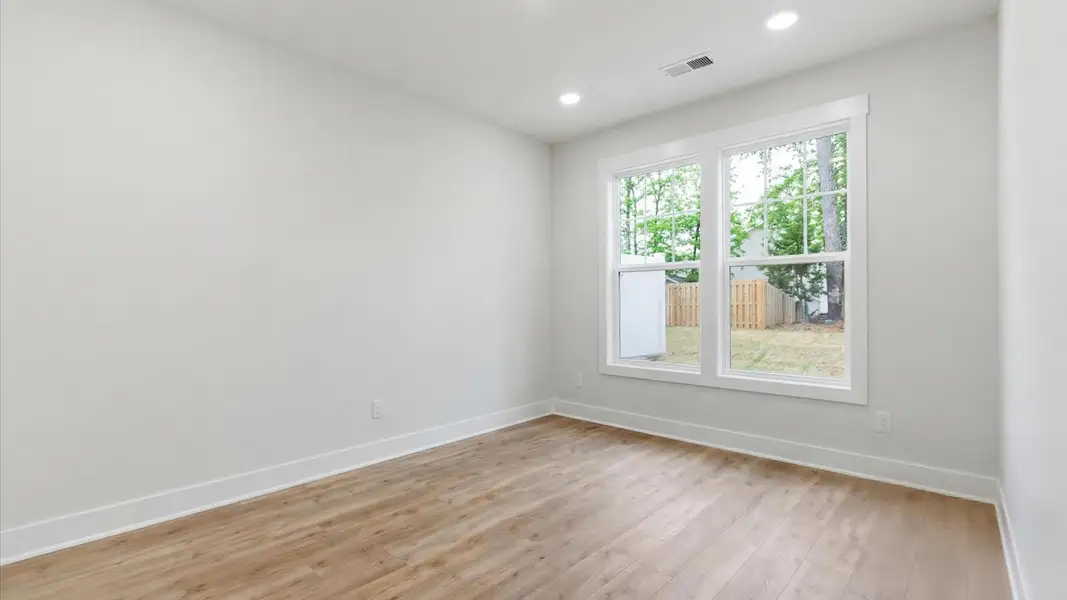 Elegant primary suite with hardwood flooring and superior natural light in this accomplished DRB Homes design