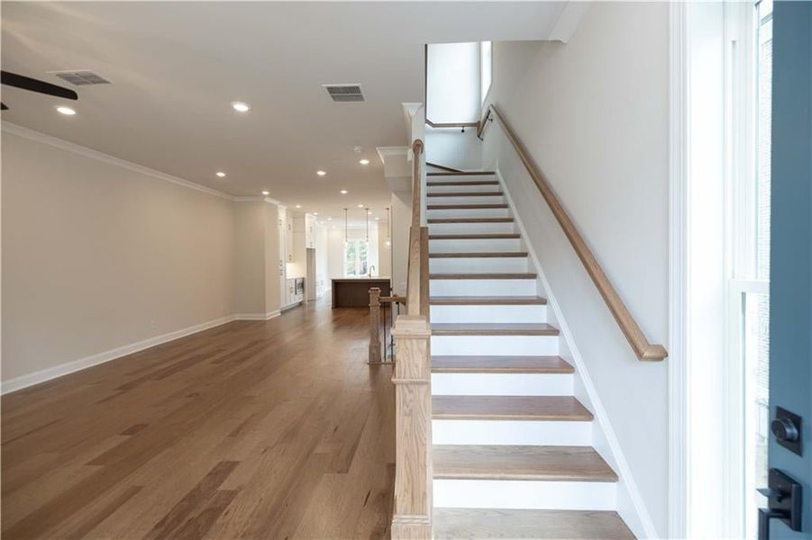 Staircase with crown molding and hardwood / wood-style floors