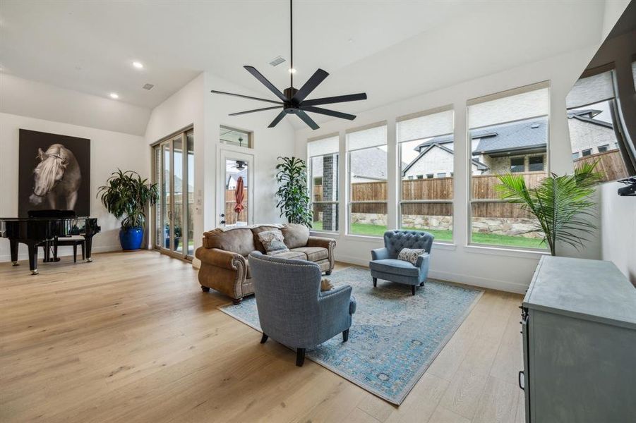 Living room with vaulted ceiling, ceiling fan, light wood-style flooring, baseboards, and recessed lighting