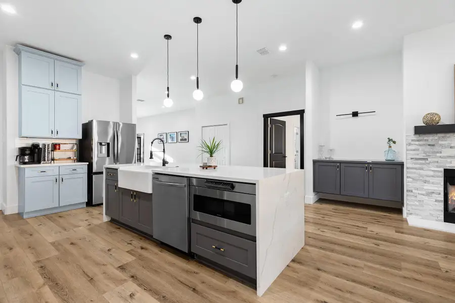 Kitchen featuring gray cabinetry, a kitchen island with sink, hanging light fixtures, stainless steel appliances, and recessed lighting