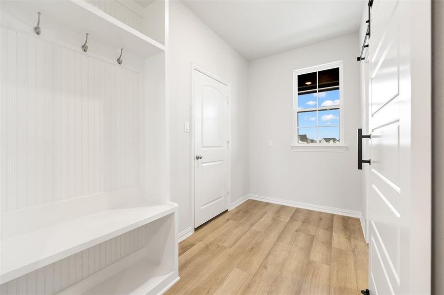 Mudroom with light wood finished floors and a barn door