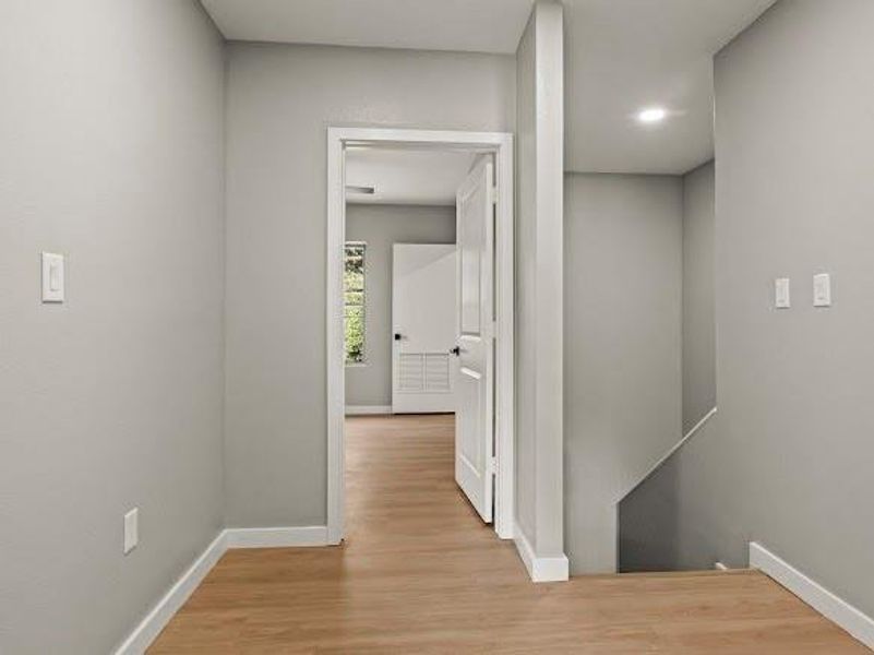Hallway featuring light wood finished floors and an upstairs landing