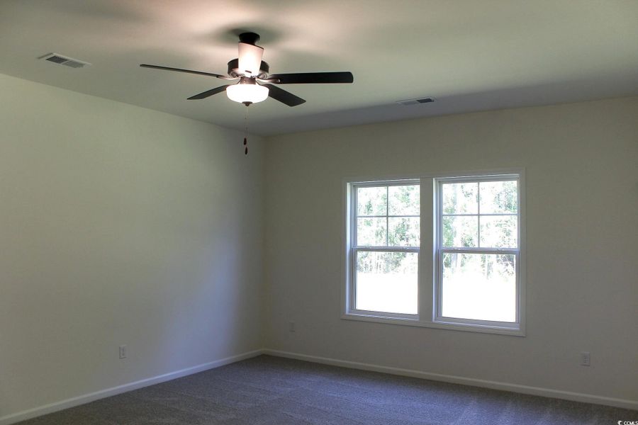 Empty room with dark colored carpet and a ceiling fan Empty room with dark colored carpet and a ceiling fan