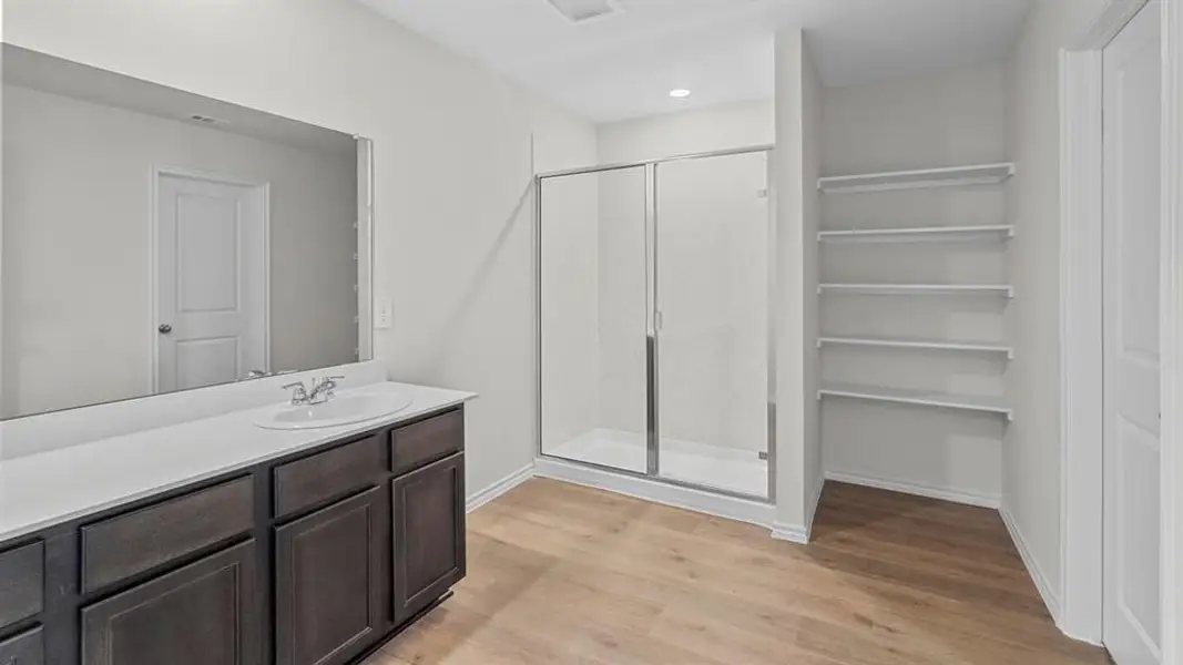 Bathroom featuring a stall shower, vanity, light wood finished floors, a closet, and recessed lighting