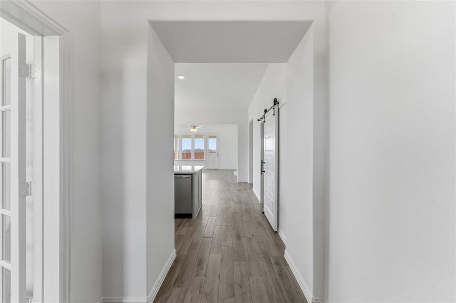 Hallway featuring a barn door, dark wood-type flooring, and recessed lighting