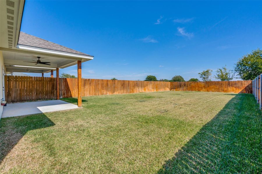 Fenced backyard featuring a ceiling fan and a patio Fenced backyard featuring a ceiling fan and a patio