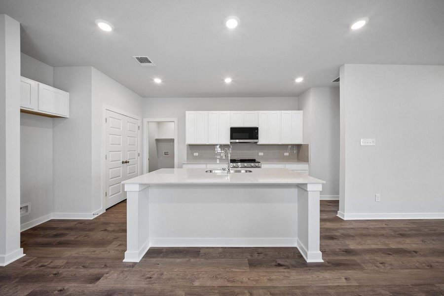 A contemporary kitchen features a spacious island and dark wood flooring, offering both style and functionality. A contemporary kitchen features a spacious island and dark wood flooring, offering both style and functionality.