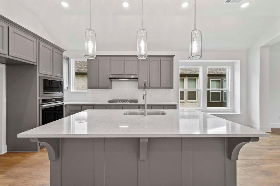 Kitchen with a sink, appliances with stainless steel finishes, gray cabinetry, and tasteful backsplash