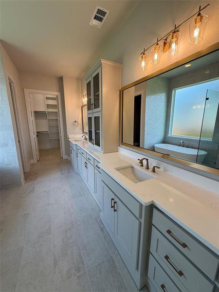 Bathroom featuring double vanity, a bath, and a spacious closet Bathroom featuring double vanity, a bath, and a spacious closet