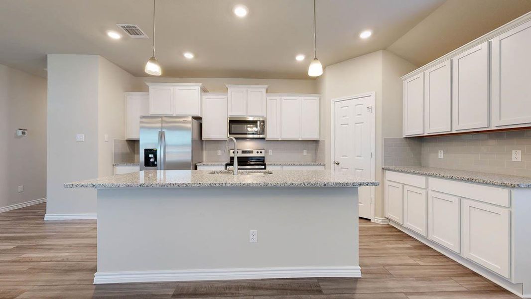 Contemporary kitchen featuring a spacious island with a light-toned countertop, white cabinetry, stainless steel appliances, a subway tile backsplash, and wood-finish flooring
