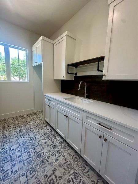 Patterned tile flooring and crisp cabinetry define this functional utility space.