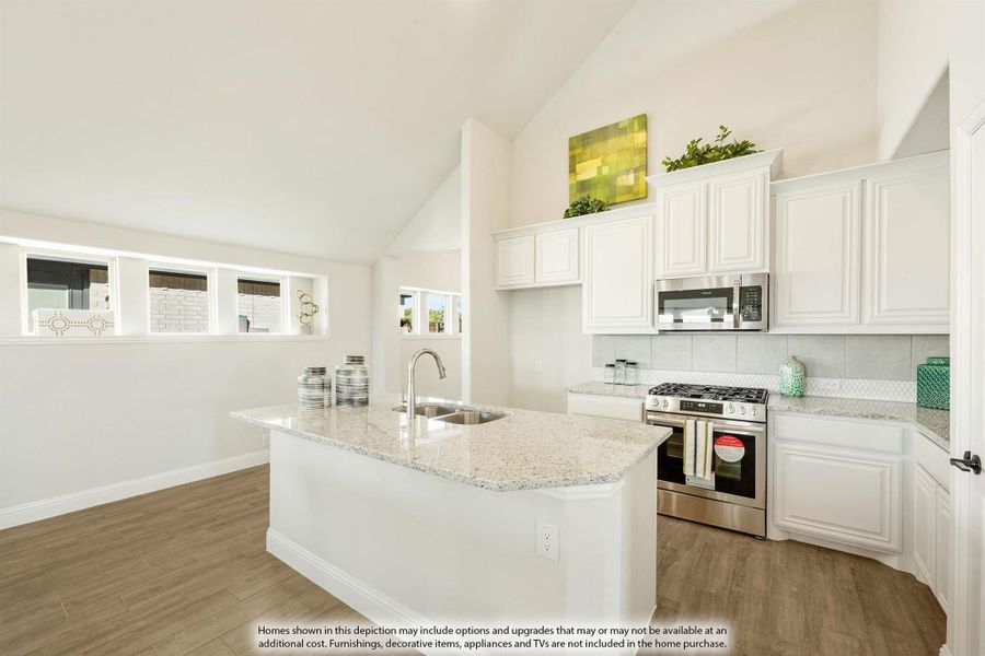 Kitchen with white cabinets, granite island with sink, stainless steel appliances, and vaulted ceiling over wood-look floors