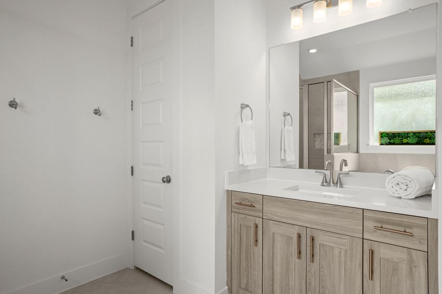 A sleek vanity with ample storage anchors this bright, well-appointed bathroom.
