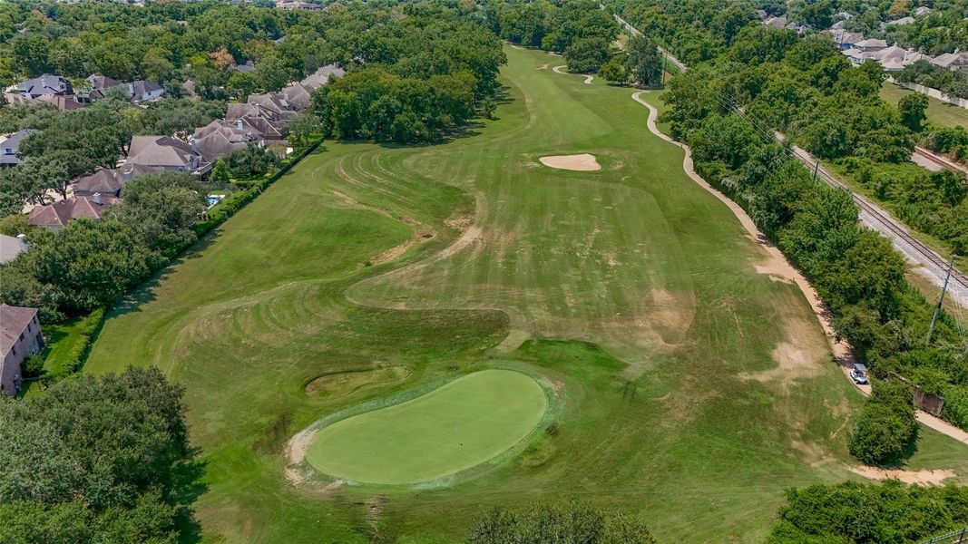 This aerial photo showcases a lush golf course with a pond, surrounded by mature trees and adjacent residential homes, offering a scenic and serene environment for potential home buyers. This aerial photo showcases a lush golf course with a pond, surrounded by mature trees and adjacent residential homes, offering a scenic and serene environment for potential home buyers.