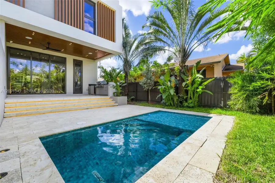 Modern exterior featuring a swimming pool, travertine deck, built-in outdoor kitchen, wood-panel soffit, and floor-to-ceiling sliding glass doors Modern exterior featuring a swimming pool, travertine deck, built-in outdoor kitchen, wood-panel soffit, and floor-to-ceiling sliding glass doors