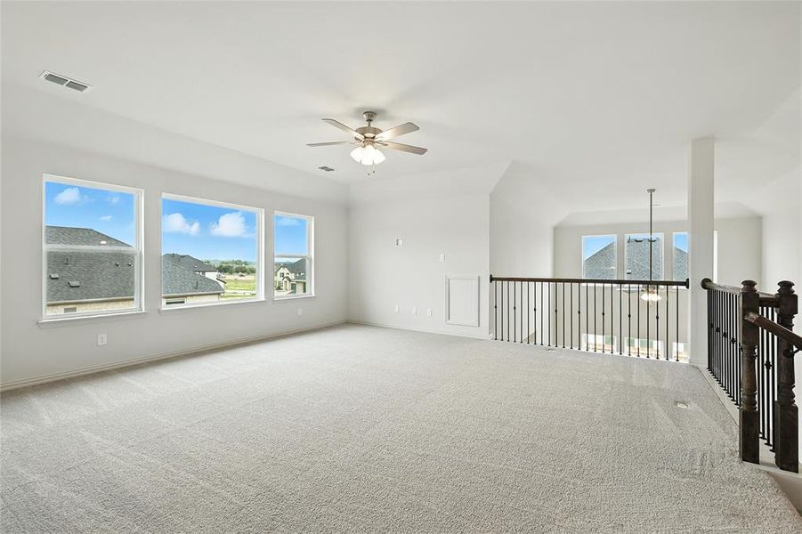 Carpeted empty room featuring a ceiling fan and plenty of natural light