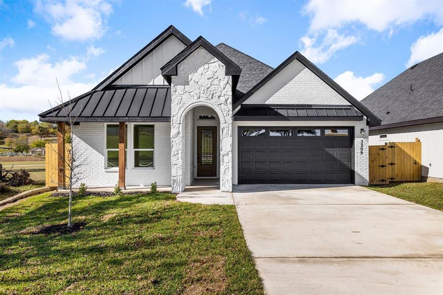 Modern farmhouse style home featuring a garage and a front lawn