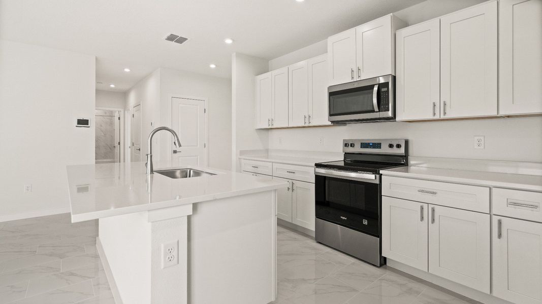 Bright kitchen with white cabinetry, quartz countertops, and center island in the Castaway model