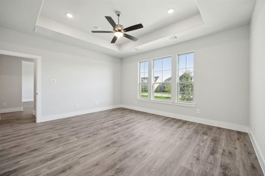 Empty room featuring hardwood / wood-style floors, ceiling fan, and a tray ceiling