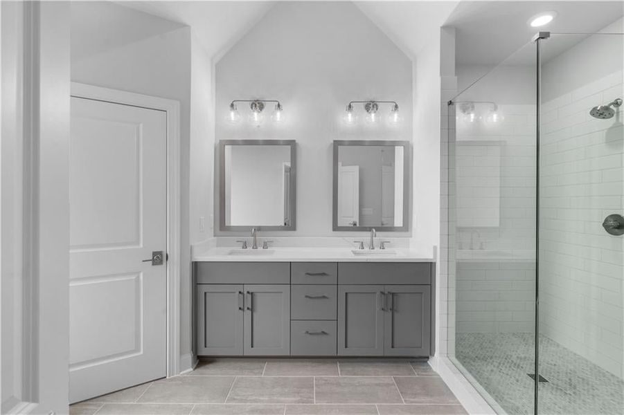 Full bathroom featuring a stall shower, double vanity, light tile patterned floors, vaulted ceiling, and recessed lighting Full bathroom featuring a stall shower, double vanity, light tile patterned floors, vaulted ceiling, and recessed lighting