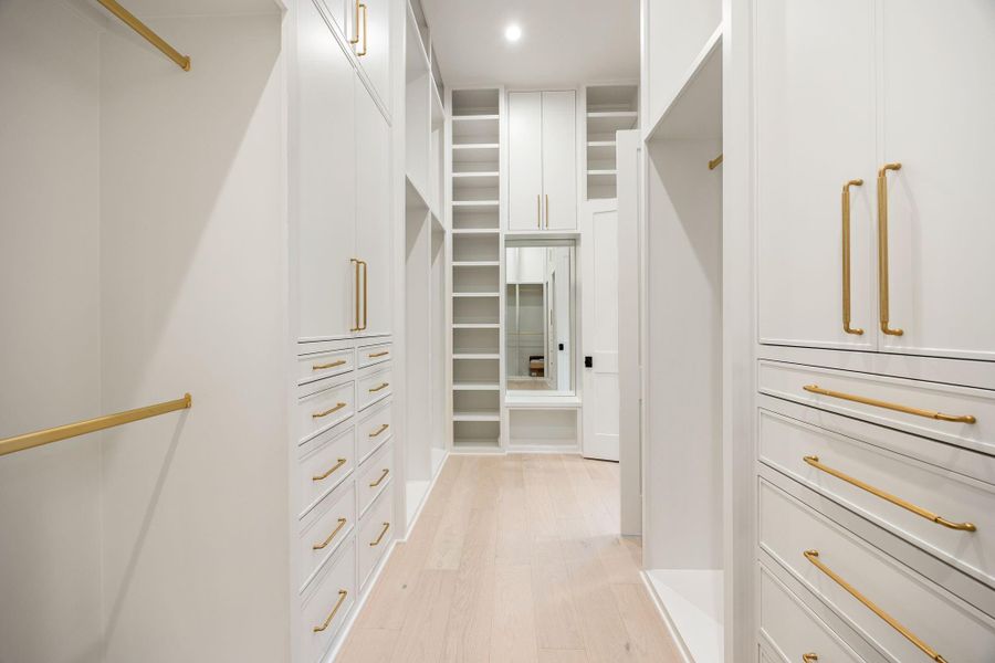 This spacious walk-in closet is designed for ultimate organization and accessibility, featuring custom built-ins, drawers, and open shelving throughout. Clean lines and a bright palette enhance visibility and function. The highlight is the floor-to-ceiling storage system, offering exceptional capacity while maintaining a streamlined and elegant aesthetic.
