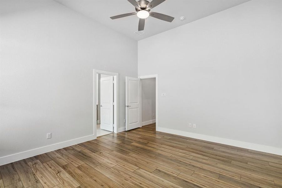 Spare room featuring hardwood / wood-style flooring, ceiling fan, and a towering ceiling