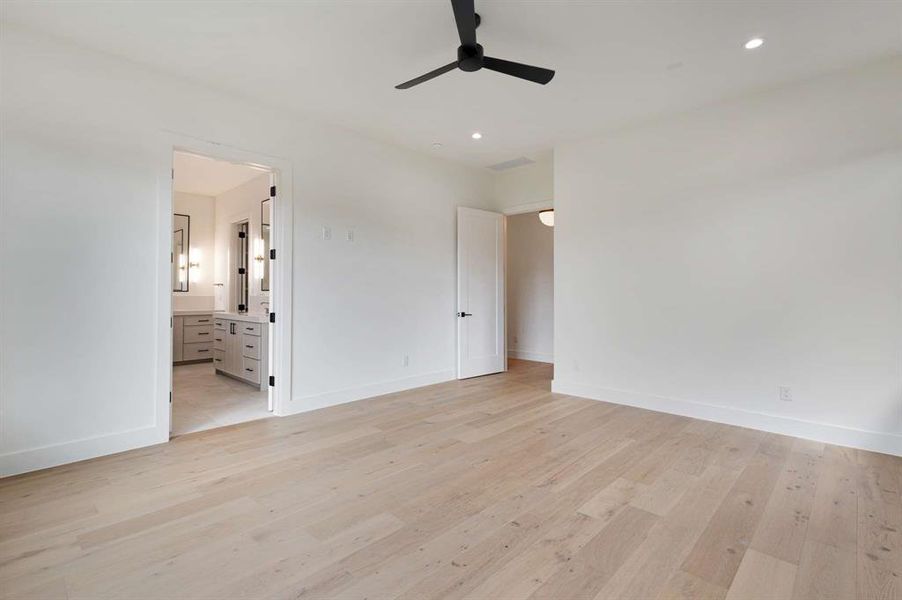 Unfurnished bedroom with light wood-type flooring, connected bathroom, and ceiling fan