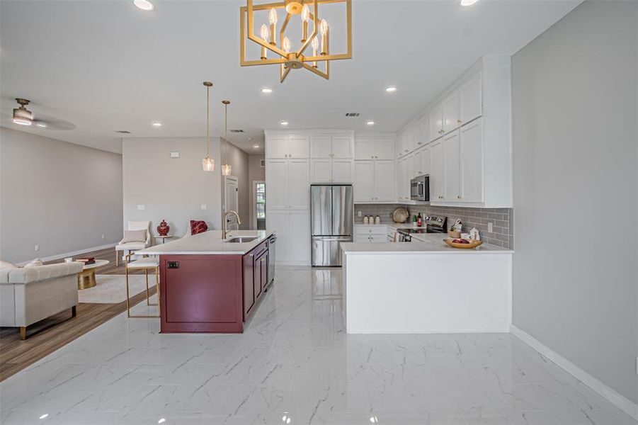 Kitchen with open floor plan, stainless steel appliances, a kitchen breakfast bar, light marble finish flooring, and decorative backsplash