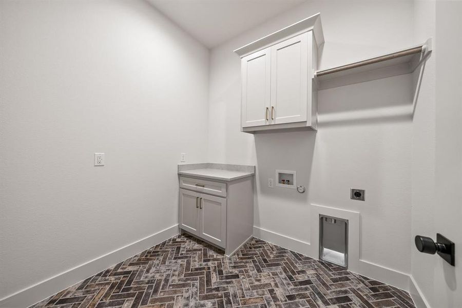 Laundry room featuring herringbone tile flooring, white shaker cabinetry, a light-toned countertop, and an integrated clothes hanging rod