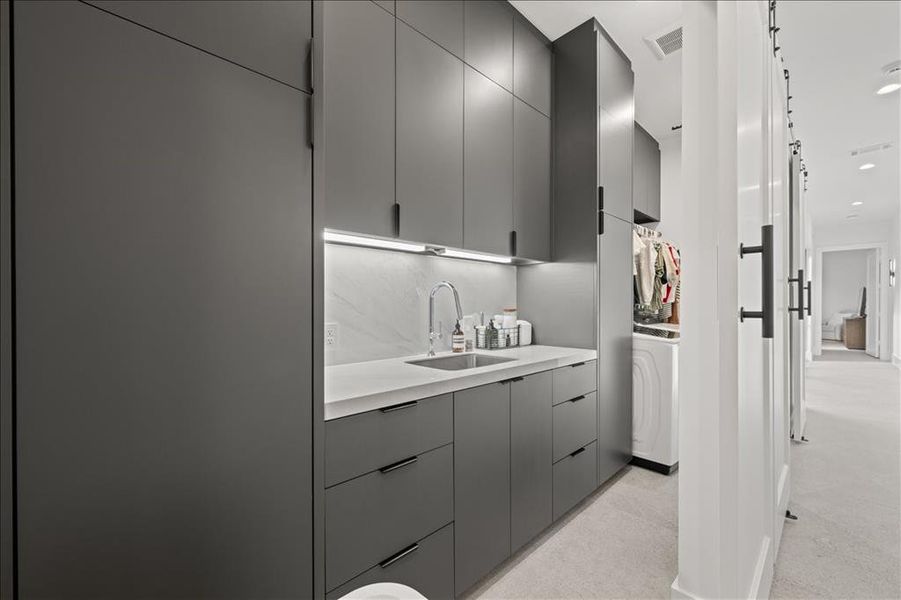 Laundry features wash sink & modern cabinets, gray cabinetry, and washer / dryer