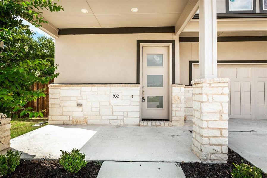 Entrance to property with a porch, stone siding, and stucco siding
