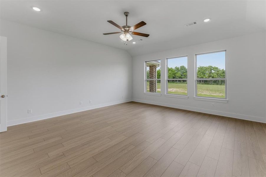Spacious room featuring wood-finish flooring, a ceiling fan, recessed lighting, and three large windows Spacious room featuring wood-finish flooring, a ceiling fan, recessed lighting, and three large windows