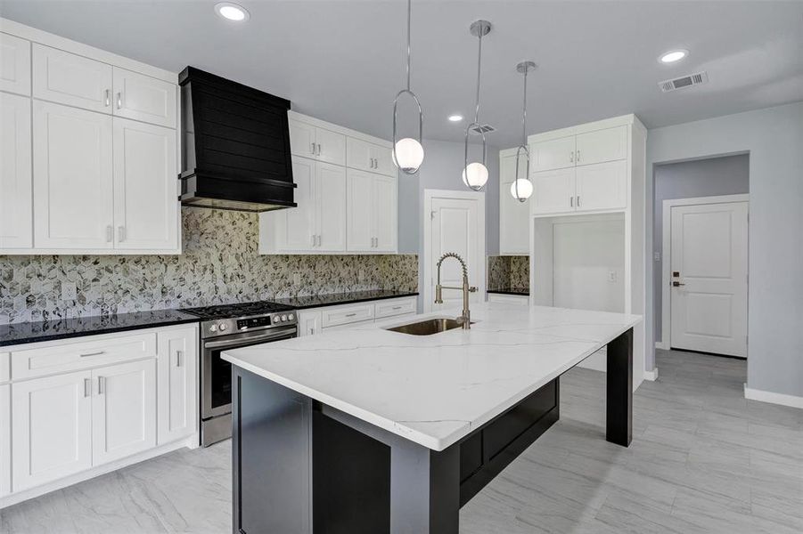 Kitchen with decorative backsplash, gas stove, custom range hood, a kitchen island with sink, and recessed lighting