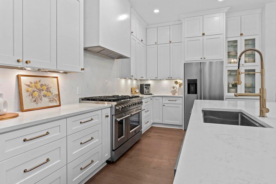 Kitchen with sink, custom exhaust hood, white cabinetry, premium appliances, and dark hardwood / wood-style floors