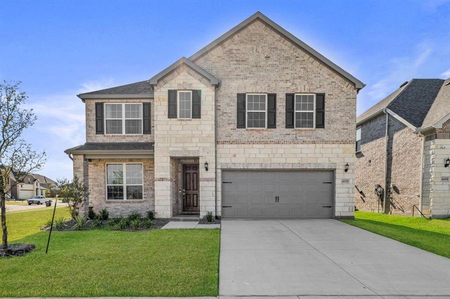 View of front of home with brick siding, a front lawn, an attached garage, and concrete driveway