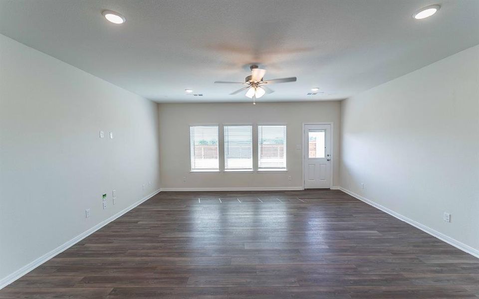 Spacious room featuring wood-finish flooring, recessed lighting, and a ceiling fan