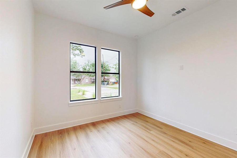 Bright interior space featuring wood-finish flooring, white walls, and a ceiling fan Bright interior space featuring wood-finish flooring, white walls, and a ceiling fan