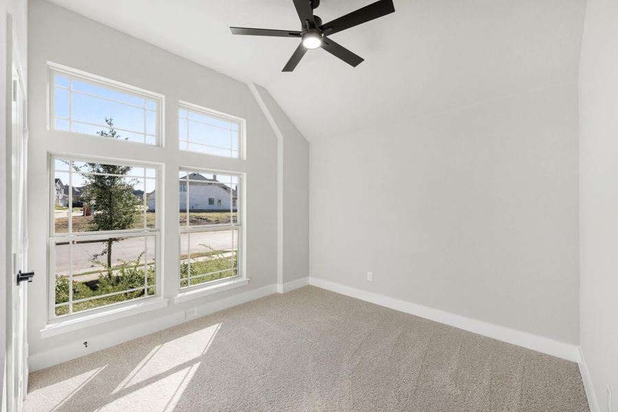 Empty bedroom with vaulted ceiling, black ceiling fan, large windows, and beige carpet