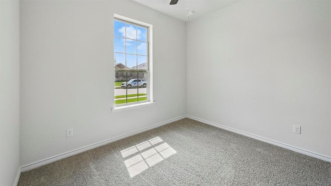 Carpeted spare room with baseboards and a ceiling fan
