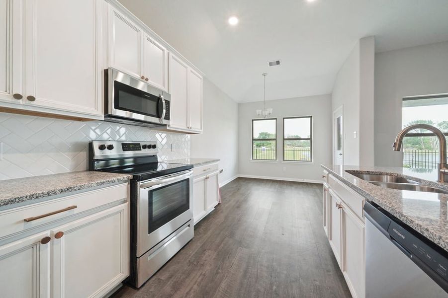 Kitchen with white cabinets, granite countertops, stainless steel appliances, and dark hardwood floors